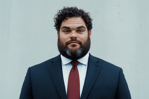 Portrait of a confident businessman with curly hair and beard wearing a suit and red tie against a neutral background photo