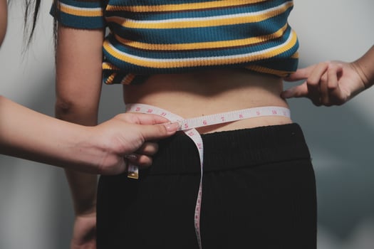 A woman measuring her waist with a tape measure photo