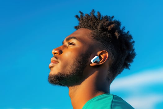 Young Man with Earbuds in Outdoor Setting, Focused and Meditative Pose Against Blue Sky, Concept of Relaxation, Music, and Mindfulness photo