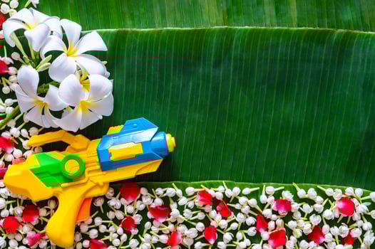 Water gun with flowers on banana leaves background for Thailand Songkran festival concept. photo