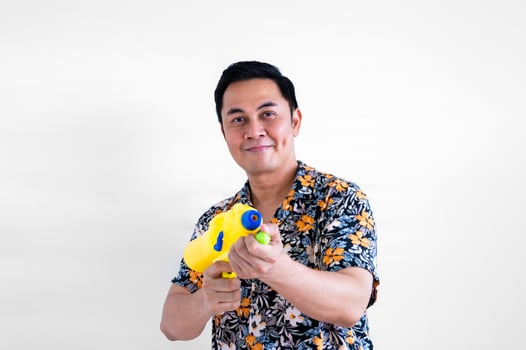 Thai male holding blurred focus of water gun with colorful shirt for Thailand Songkran festival concept. photo