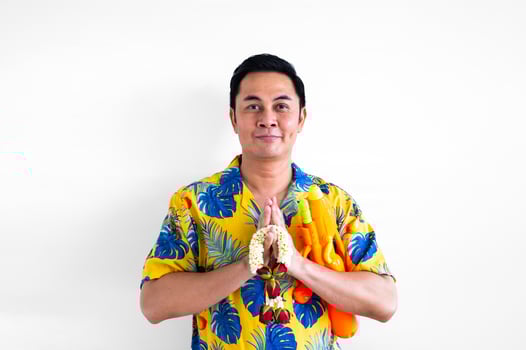 Thai male doing pray pose with blurred focus of garland and water gun with colorful shirt for Thailand Songkran festival concept. photo
