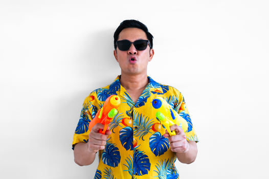 Thai male holding two blurred focus of water guns wearing yellow shirt for Thailand Songkran festival concept. photo