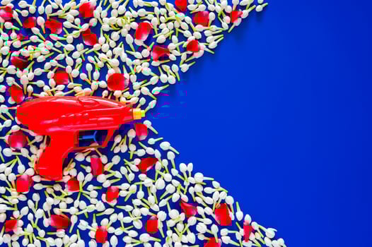 Water gun for Thailand Songkran festival celebration on blue empty background with jasmine and rose petal. photo