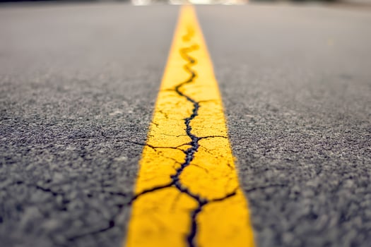 Close-up shot of a yellow line on an asphalt road, symbolizing direction, journey, and movement in a conceptual style photo