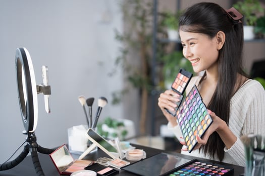 beauty and makeup concept - asian woman holding makeup products and looking at camera photo