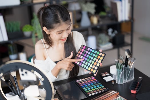 a woman is holding a palette of makeup products. photo