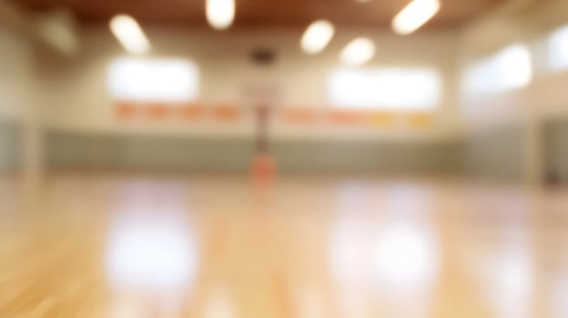 Indoor Gymnasium Court with Polished Wood Flooring and Basketball Hoop Stands in Soft Focus photo