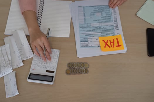 Woman managing finances and tax documents with a calculator photo