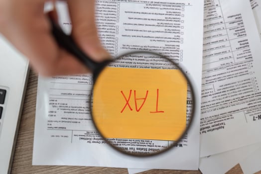 Magnifying glass revealing the word 'TAX' on financial documents, highlighting critical information for filing. photo