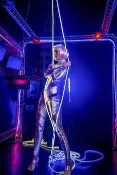 Blonde as a cyber robot. Girl in shining silver armor in neon. Blonde with fantastic makeup and image in dark key and colored light, posing in cyberspace. her head is wrapped in glowing wires photo
