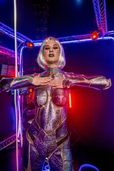 blonde as cyber robot. Girl in shining silver armor in neon. Blonde with fantastic makeup and image in dark key and color light, posing in cyberspace. screens and wires glow around photo