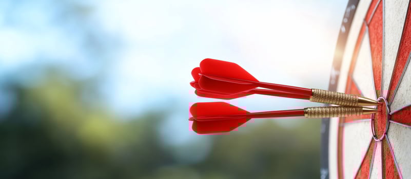 Two red darts hitting the bullseye on a dartboard outdoors. photo