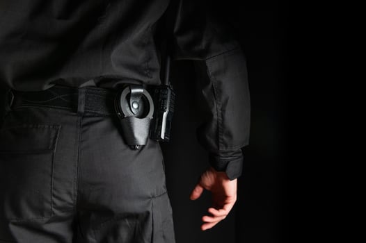 security guard controlling the premises. bodyguard in black uniform on black background, with handcuffs on his belt photo