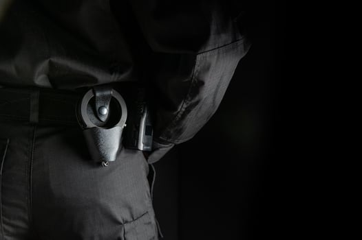 security guard controlling the premises. bodyguard in black uniform on black background, with handcuffs on his belt photo
