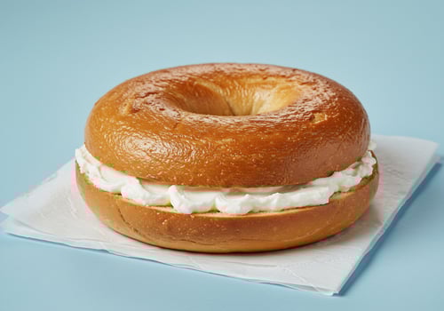 Cream cheese bagel on pale blue background photo
