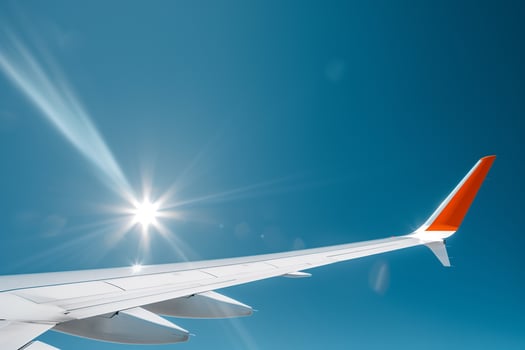 Jet wing cutting through a clear blue sky with sun reflecting off its edge photo
