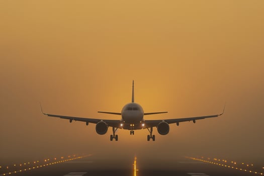 Fog-shrouded jet descends at sunrise with landing lights cutting through the mist photo