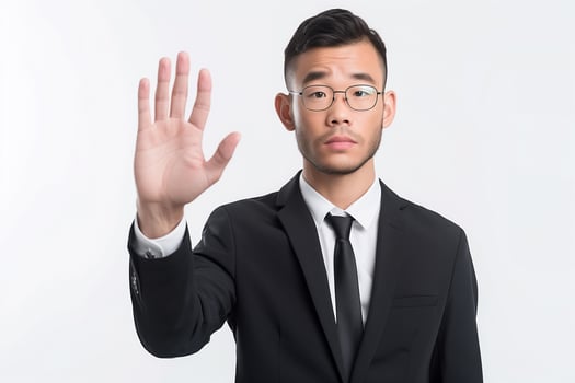 Serious young East Asian male analyst gestures stop with palm while wearing formal clothing on a white background photo