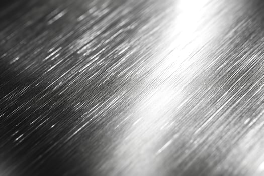 Close-up of brushed metal surface with reflective highlights, showcasing its sleek and modern aesthetic. photo