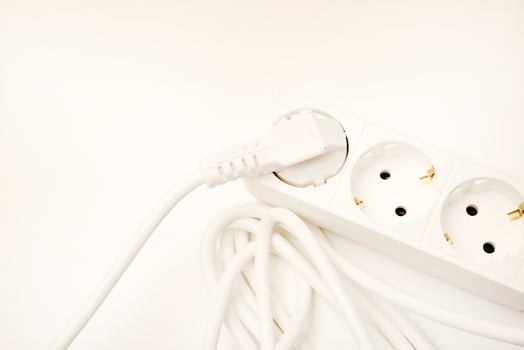 A three-plug electrical strip with a white cord showcased on an ivory-toned background. photo