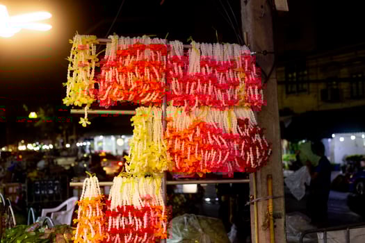 Thai Garlands of flowers hang in neat rows on a shelf waiting to be sold by the roadside in bangkok thailand photo