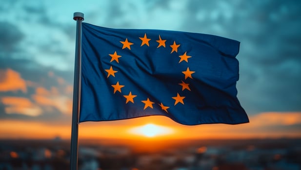 European Union flag waving at sunset. The European Union flag flutters gracefully against a vibrant sunset sky, showcasing stars and colors. photo