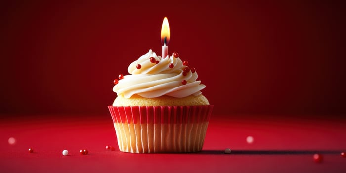 Colorful cupcake with a lit candle on a vibrant red background creates a festive atmosphere for celebration photo