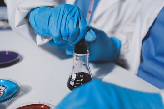 A person in blue gloves is holding a test tube photo