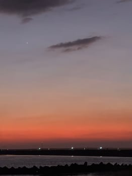 Dark twilightover Kelan Beach, Bali, with calm ocean waves and a scenic breakwater. A tranquil coastal scene with warm hues and serene atmosphere. photo