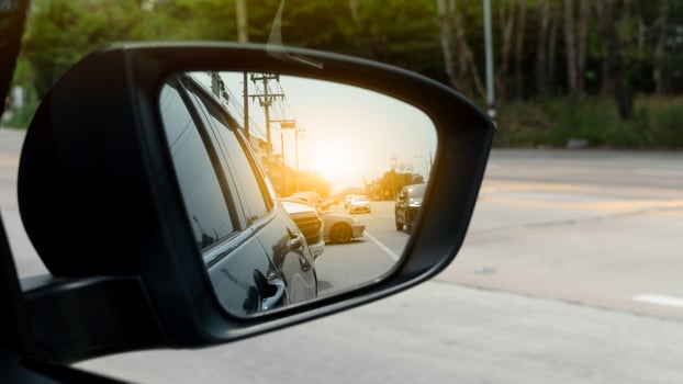Mirror view of dark car. Reflection in the mirror of another car driving on the road with orange blur light. photo