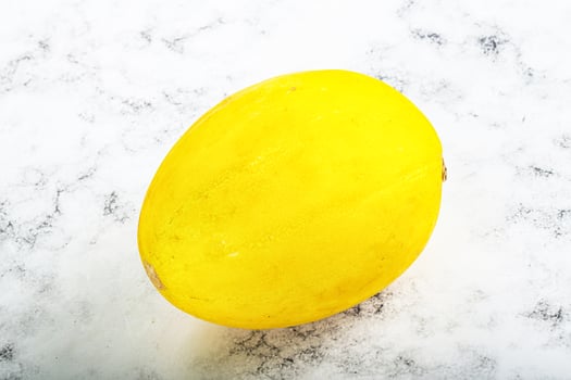 A yellow fruit on a white marble surface photo