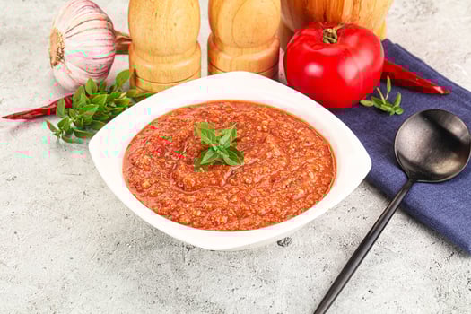 A bowl of tomato sauce with a spoon and a knife photo
