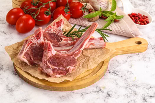 Raw lamb chops on a wooden cutting board photo