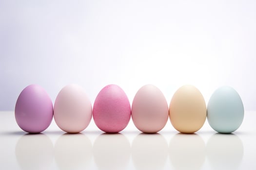 A row of eggs with different colors, including pink, yellow, and green on white background with reflections photo