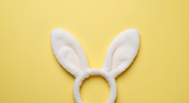 Rabbit Ears on a Light Yellow Background for Easter Joy. Cute bunny ears peeking out on a bright pastel background, celebrating Easter traditions, the arrival of spring photo