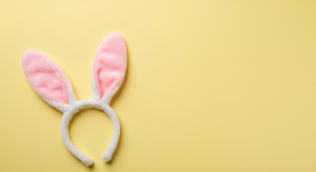 Happy Easter Bunny Ears on Pastel Yellow Background. A minimalist flat lay with bunny ears representing the Easter holiday, springtime joy, and festive renewal photo