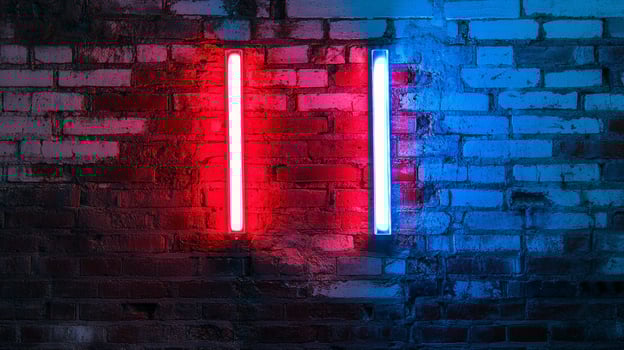 Neon light tubes in red and blue illuminating a textured brick wall creating a stark contrast of color and form against rough texture. photo