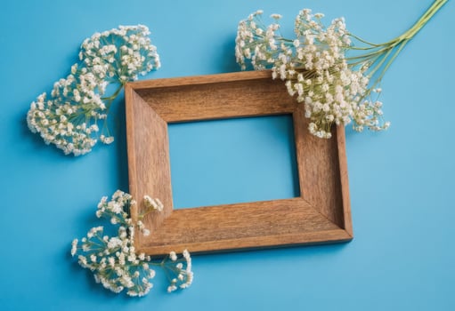 Wooden frame with baby's breath flowers on blue background photo