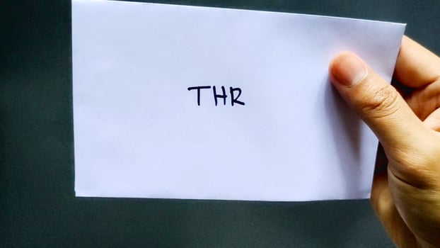 This man holding a white envelope that says THR. This envelope contains one month's salary allowance which is usually given to employees before the Islamic holidays photo