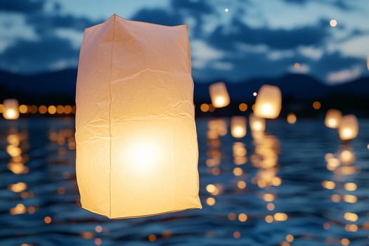 Floating lanterns illuminate a serene water surface at dusk. photo