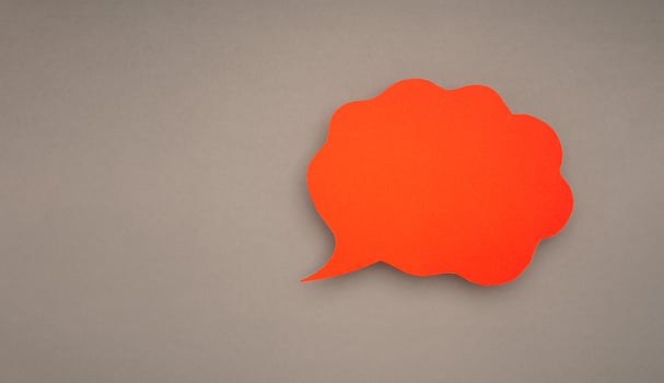 A blank red cloud speech bubble on a gray background photo