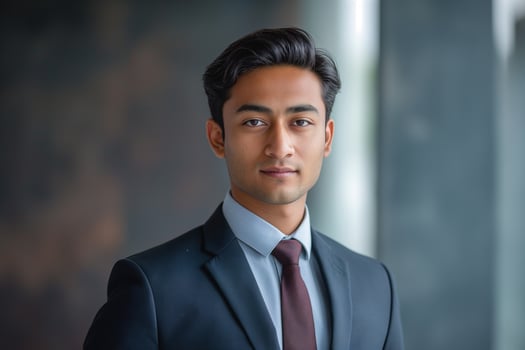 A confident young South Asian man in a business suit poses in a modern office setting, exuding professionalism and determination. photo