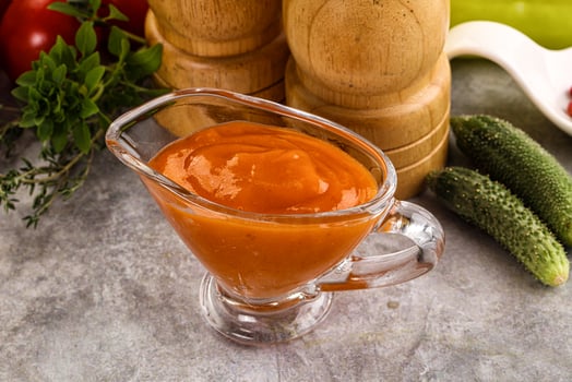 A glass of tomato sauce next to a bowl of vegetables photo