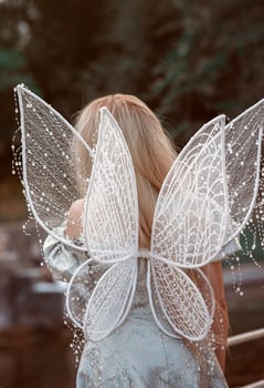 Fairy wings on a cute blonde girl. Fairy carnival costume. Back view of transparent and white beautiful fairy wings. photo