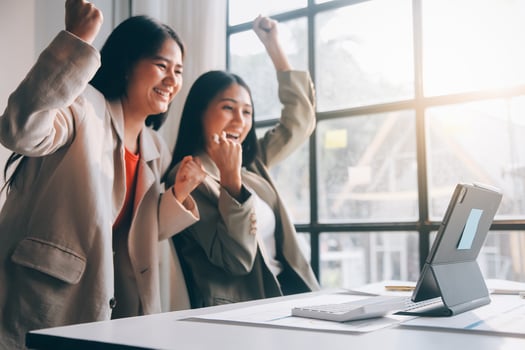 Two women are celebrating in front of a computer photo