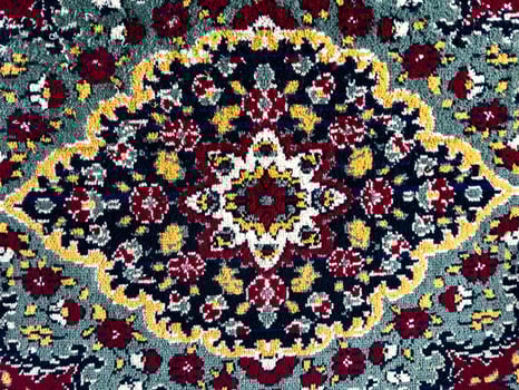 A close-up of a traditional woven carpet with an intricate floral pattern, featuring deep red, gold, green, and black tones. This classic Russian-style rug showcases detailed ornamentation, a rich photo