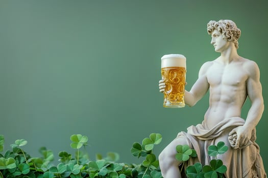 greek antique male god sculpture holding glass of tasty fresh golden beer surrounded by clovers leaves on green background with copy space photo