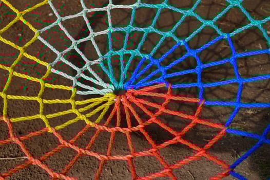 Colorful spiral web made of vibrant ropes showcases intricate artistry at a sunny outdoor setting photo