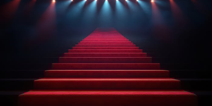 Red carpet stairs leading to an illuminated stage in a darkened venue at night photo